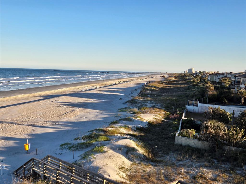 An elevated view of a sandy beach with dunes, a wooden walkway, and coastal homes — 4799 S ATLANTIC AVENUE UNIT 4080, PORT ORANGE, FL