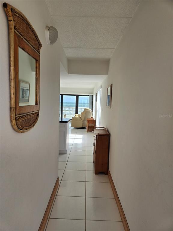 A hallway with white tile floors leads toward a living area with an ocean view — 4799 S ATLANTIC AVENUE UNIT 4080, PORT ORANGE, FL