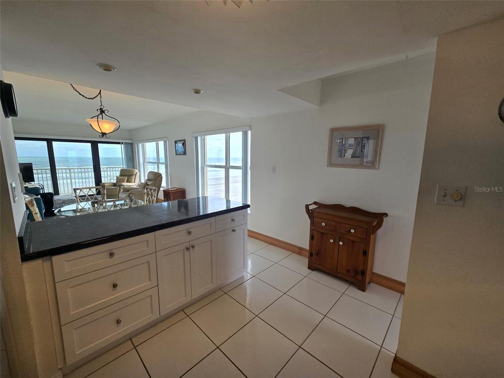 A kitchen island with a dark countertop overlooks a living area with ocean views — 4799 S ATLANTIC AVENUE UNIT 4080, PORT ORANGE, FL