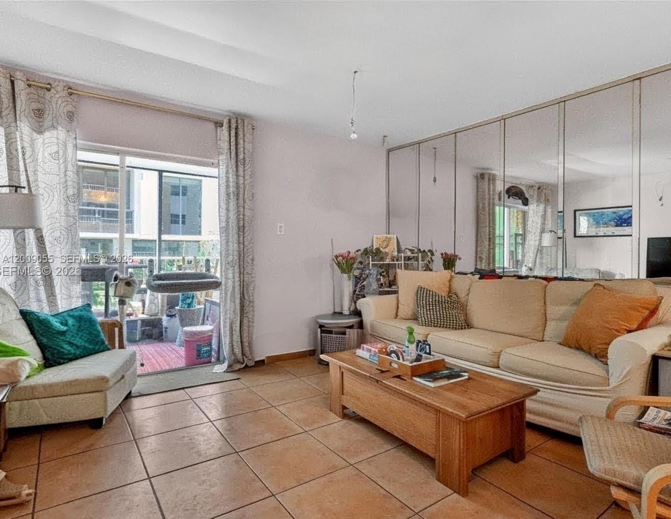 A living room features tiled floors, a beige sofa, a coffee table, and mirrored walls — 3304 Virginia St # 3D, Miami FL 33133, MIAMI, FL