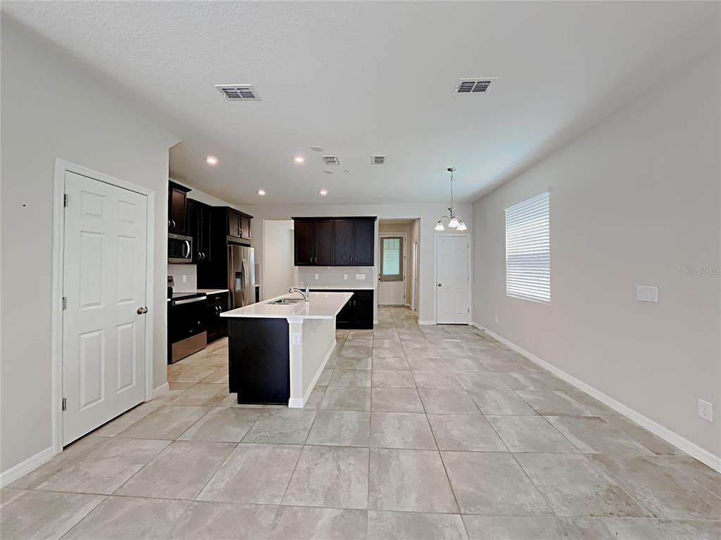 A kitchen with dark cabinetry, a white island, and light tile flooring in an open space — 11912 FOUNDERS STREET, ORLANDO, FL