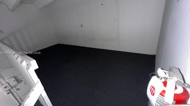 An empty room with dark carpeting, white walls, and a fire extinguisher in the foreground — 12153 SW 131st Ave, Miami FL 33186, MIAMI, FL