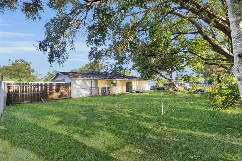 A backyard with a chain-link fence, a wooden privacy fence, and a single-story house — 14721 SW 35TH TERRACE ROAD, OCALA, FL