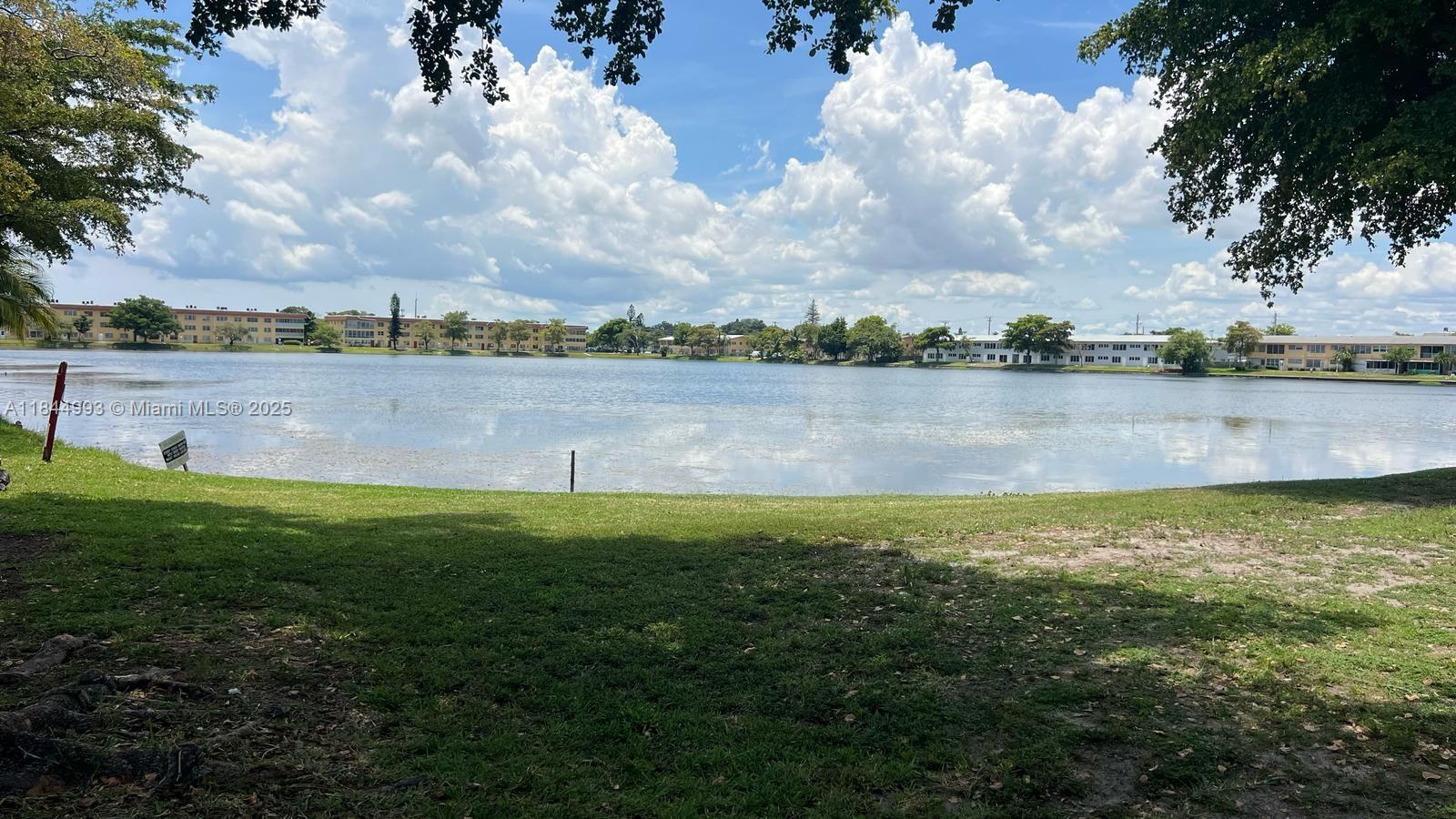 A grassy park area overlooks a large lake with apartment buildings in the background — 19080 NE 3rd Ct # 307, Miami FL 33179, MIAMI, FL