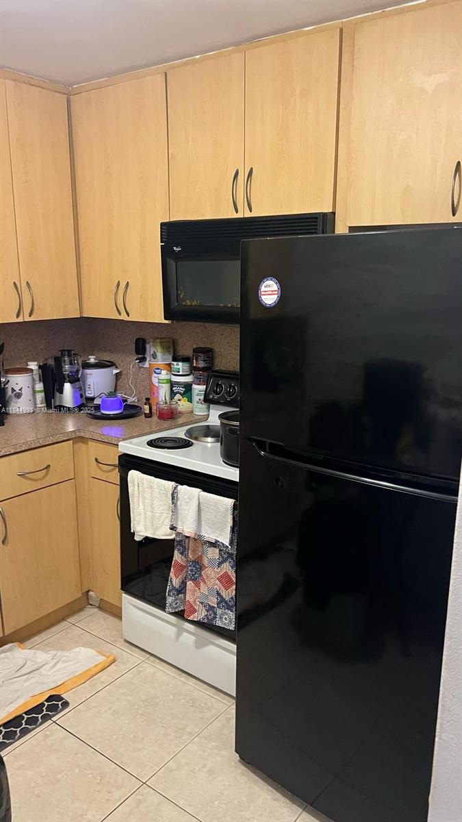A kitchen features light wood cabinets, a black refrigerator, and a white stove — 19080 NE 3rd Ct # 307, Miami FL 33179, MIAMI, FL