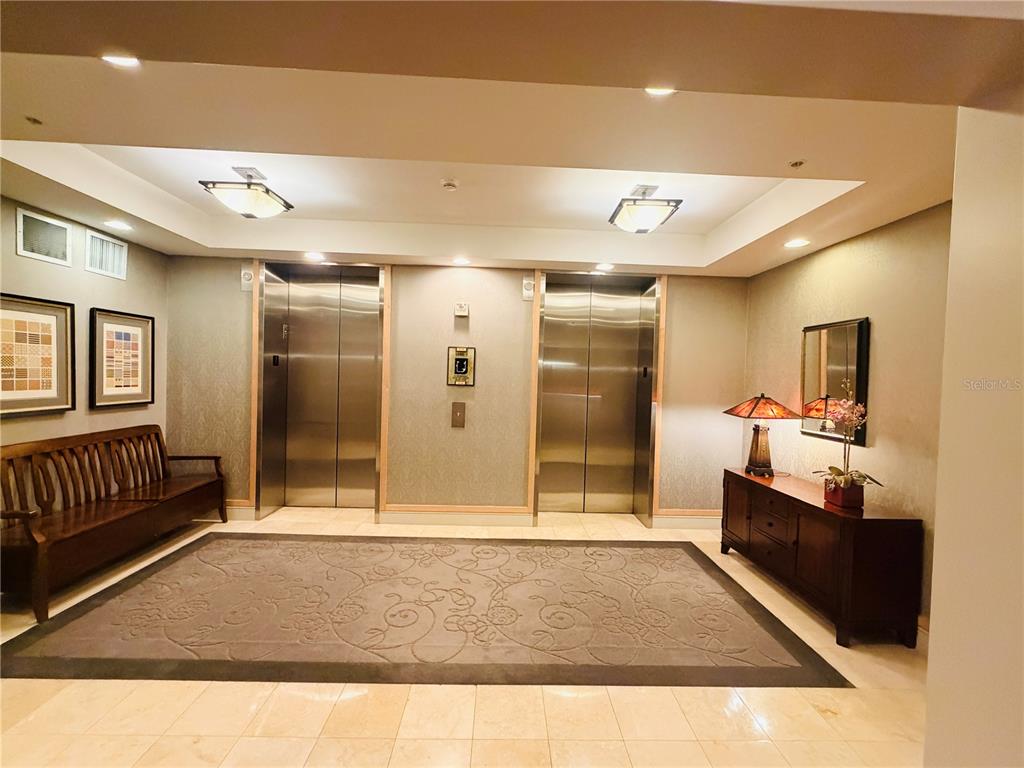 A lobby features two stainless steel elevators, a wooden bench, and a dark wood console — 2305 EDGEWATER DRIVE UNIT 1708, ORLANDO, FL