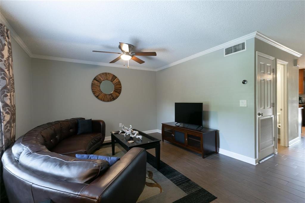 A living room features a grey sectional sofa, a coffee table, and a television console — 2478 FOREST WAY, GAINESVILLE, FL