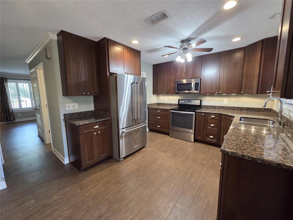 A dining room features a dark table, white chairs, a ceiling fan, and sliding doors — 2478 FOREST WAY, GAINESVILLE, FL