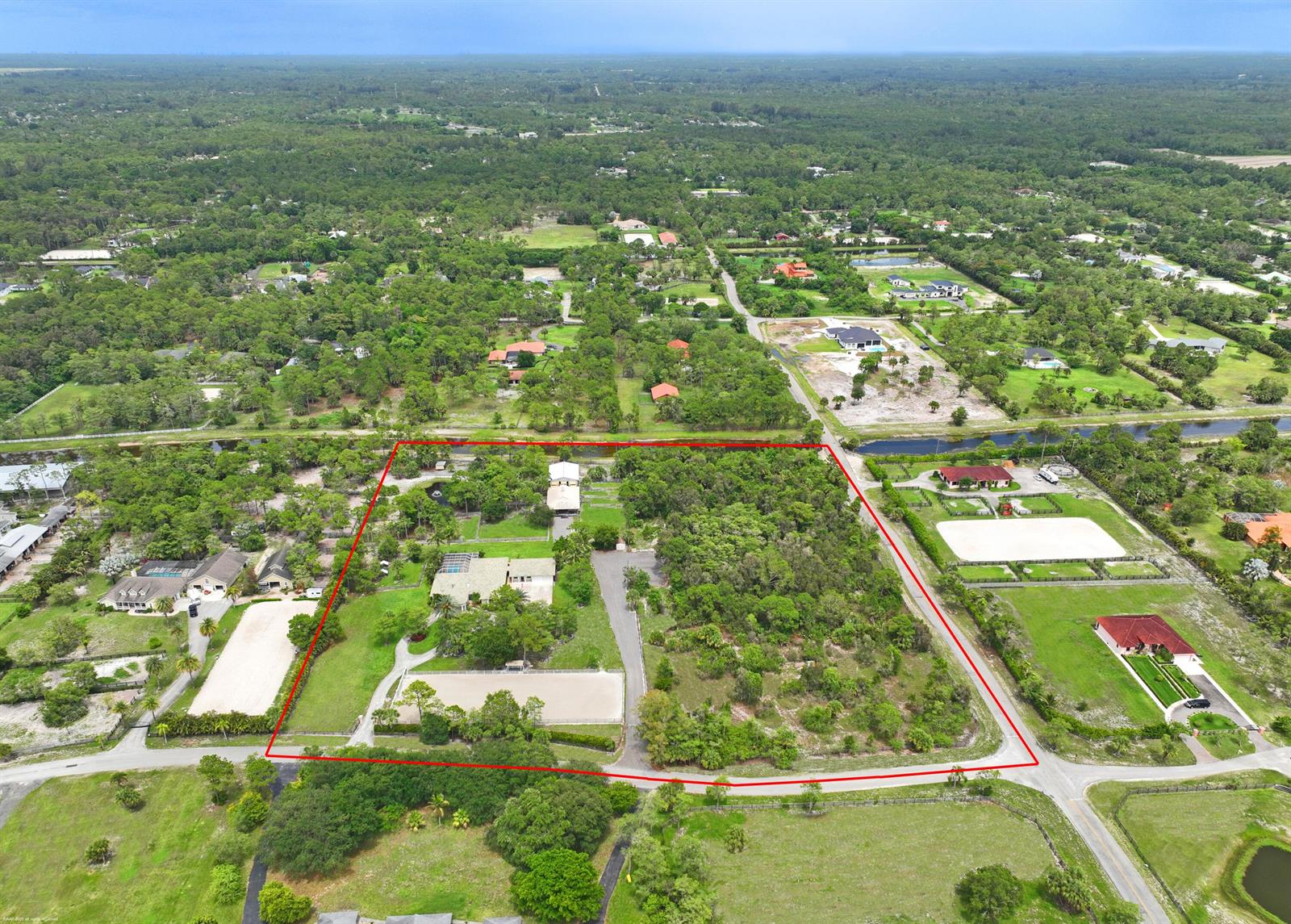 An aerial view shows a large residential property with a house, stables, and riding arena — 2560 Buck Ridge Trail, Loxahatchee FL 33470, LOXAHATCHEE, FL