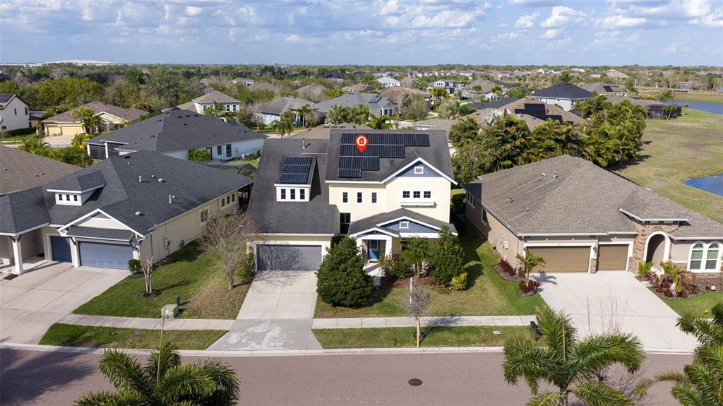 An aerial view shows a two-story suburban house with solar panels on the roof — 6313 HAVENSPORT DRIVE, APOLLO BEACH, FL