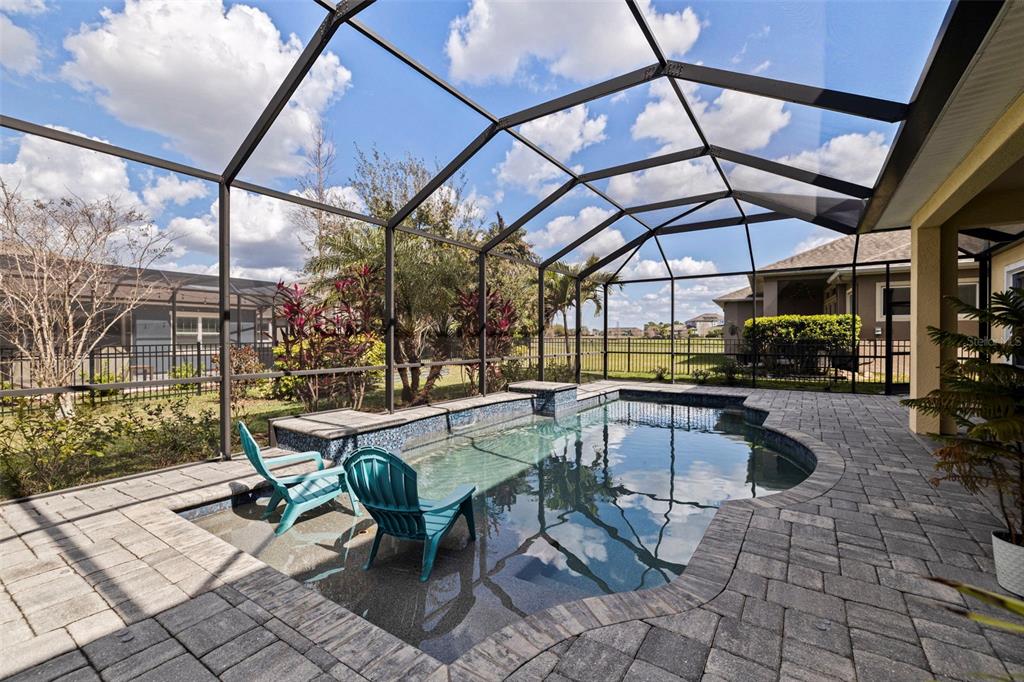 A screened-in patio features a swimming pool with a tanning ledge and two lounge chairs — 6313 HAVENSPORT DRIVE, APOLLO BEACH, FL