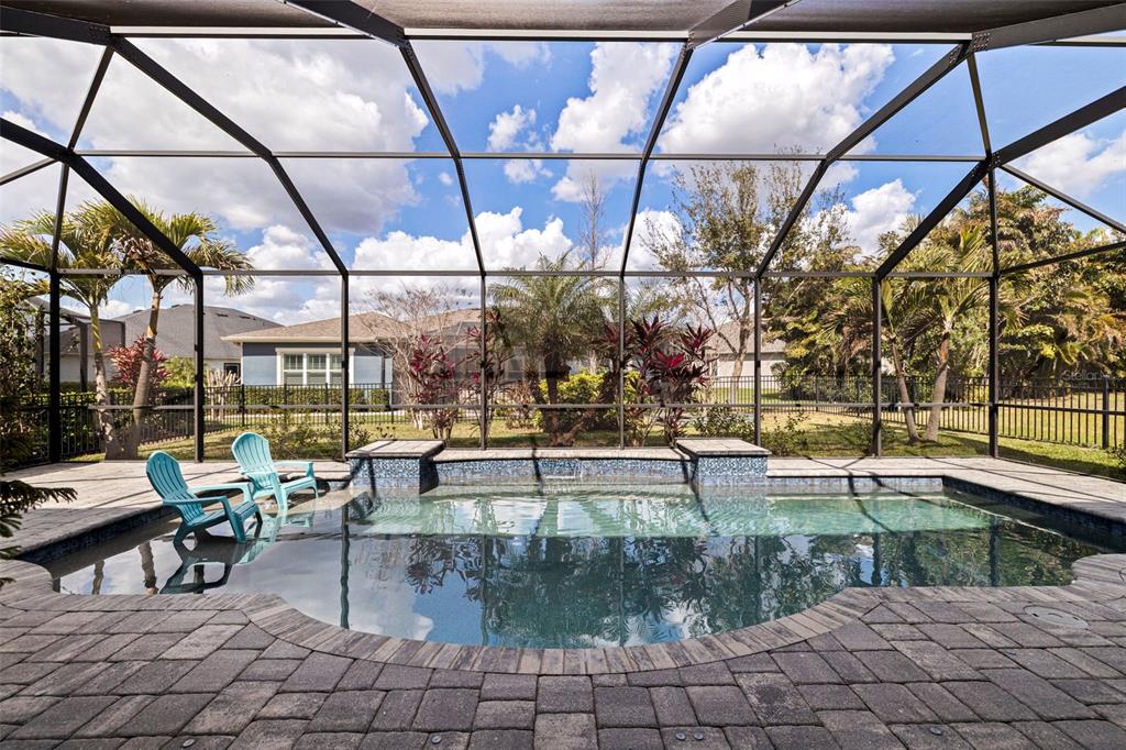 A swimming pool with a tiled water feature sits inside a screened-in patio area — 6313 HAVENSPORT DRIVE, APOLLO BEACH, FL