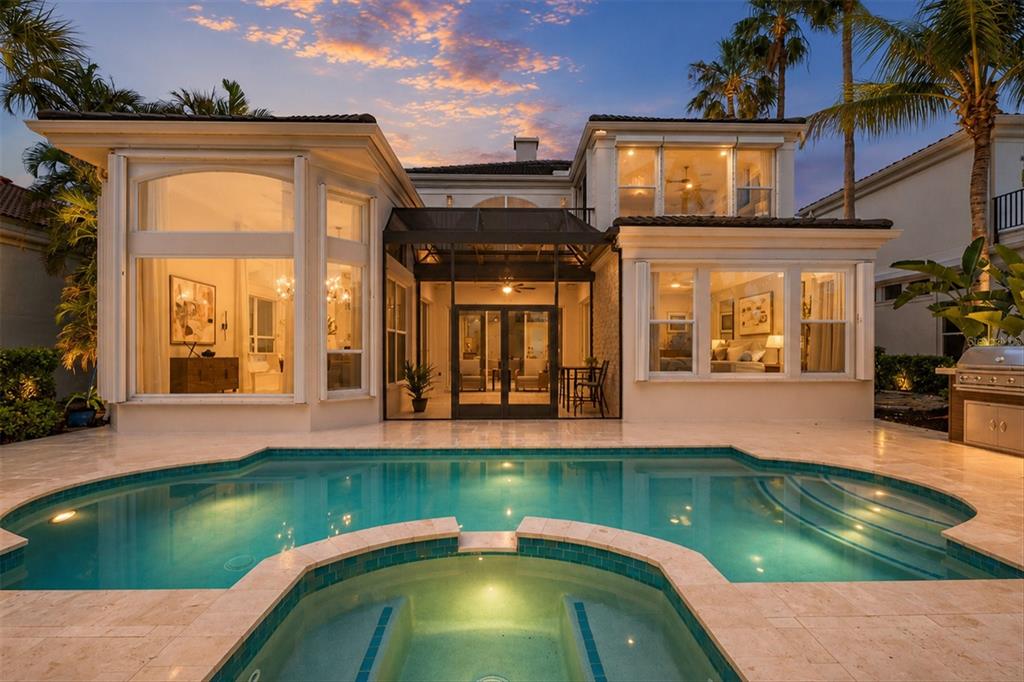 A two-story house exterior at dusk featuring a swimming pool, spa, and screened-in patio — 3606 FAIR OAKS PLACE, LONGBOAT KEY, FL