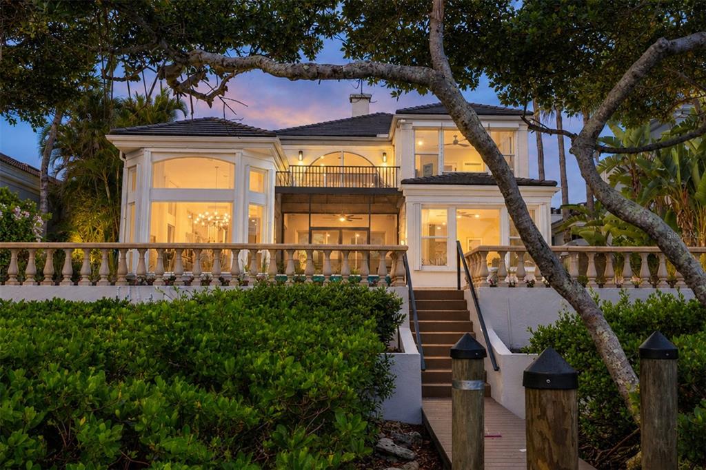 A two-story waterfront house with a balcony, large windows, and stairs leading to a dock — 3606 FAIR OAKS PLACE, LONGBOAT KEY, FL