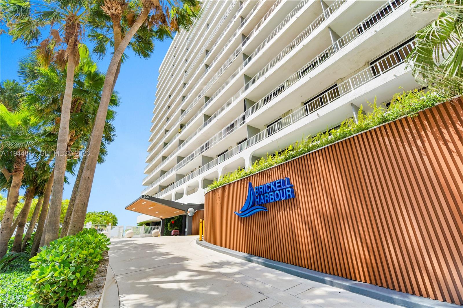 The exterior of a multi-story residential building features a curved wooden wall with signage — 200 SE 15th Rd # 5D, Miami FL 33129, MIAMI, FL