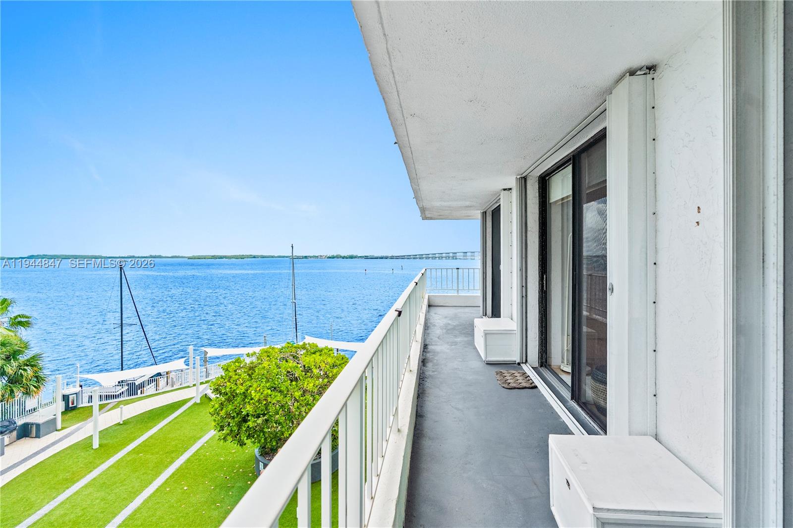 A balcony with a white railing overlooks a grassy lawn and a large body of water — 200 SE 15th Rd # 5D, Miami FL 33129, MIAMI, FL