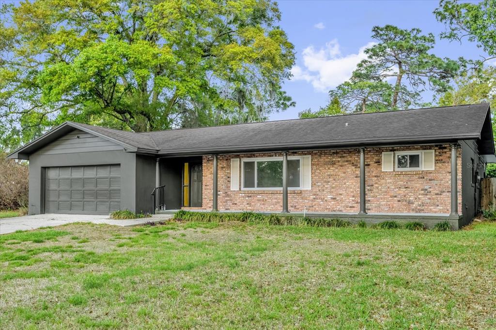 A single-story ranch-style house with a brick facade, dark gray trim, and an attached garage — 2 HUDSON COVE, LONGWOOD, FL