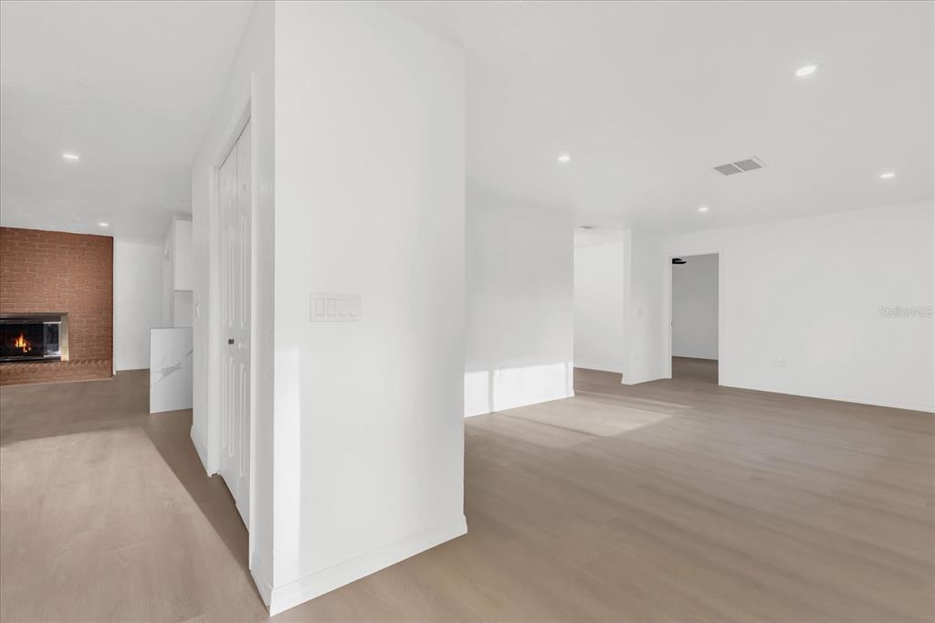 An interior view of a living area with light wood floors, white walls, and a fireplace — 2 HUDSON COVE, LONGWOOD, FL