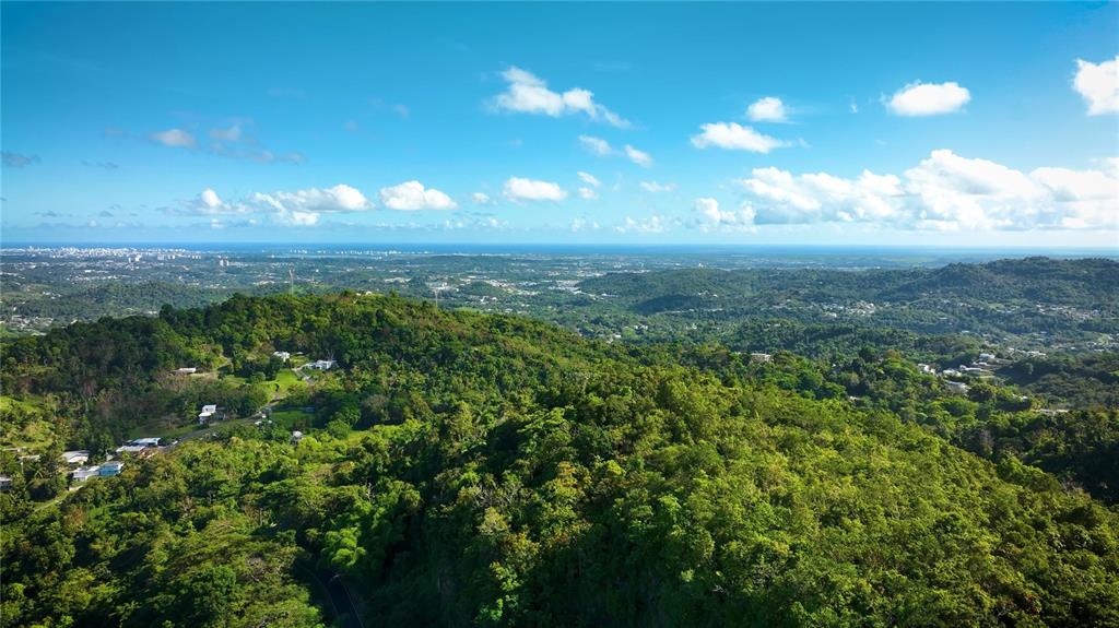 An aerial view of a lush, hilly landscape with scattered houses under a blue sky — PR181 km 53.3 SECTOR LA SILLA  CARR 941, GURABO, PR