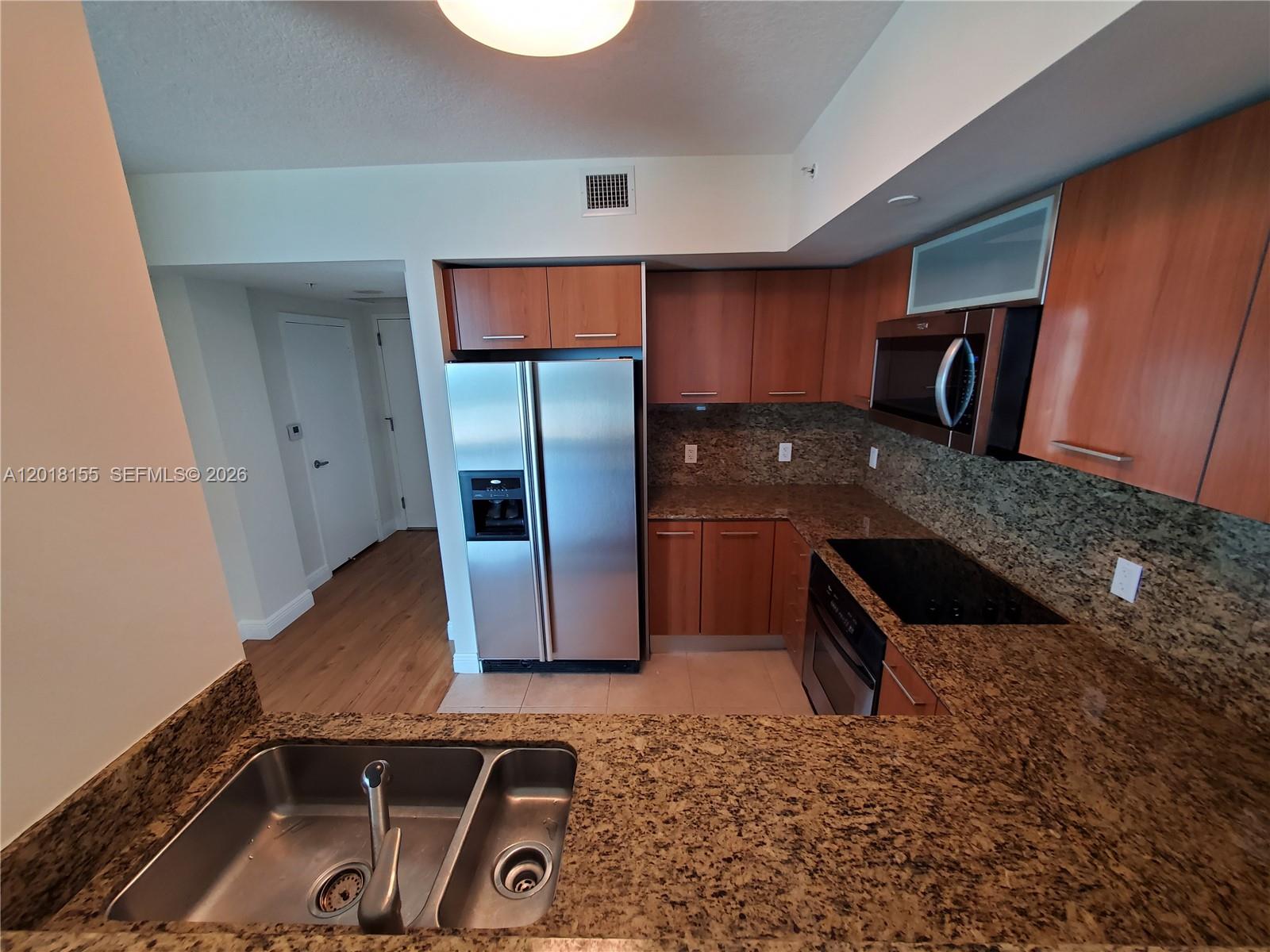 A kitchen features wood cabinets, granite countertops, stainless steel appliances, and a double-basin sink — 9066 SW 73rd Ct # 1808, Miami FL 33156, MIAMI, FL
