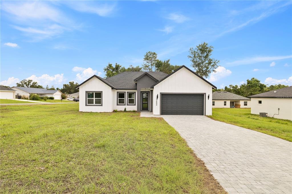 A modern single-story house with white siding, a dark gray garage, and a paved driveway — 13684 SW 43RD CIRCLE, OCALA, FL