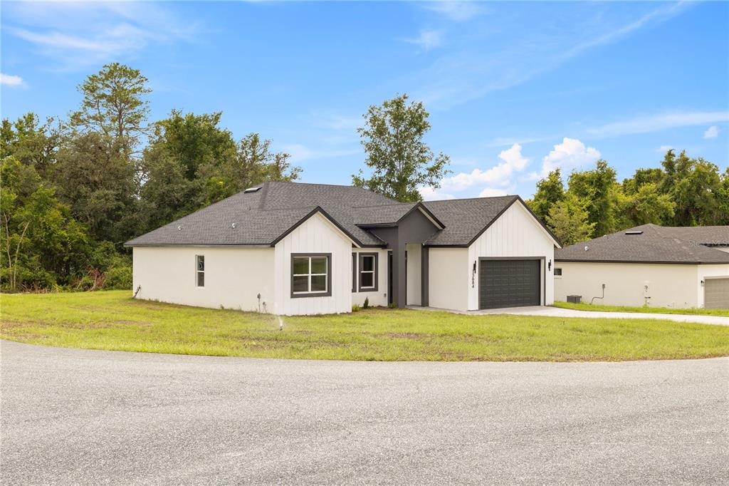A single-story house with white stucco walls, a dark roof, and a two-car garage — 13684 SW 43RD CIRCLE, OCALA, FL