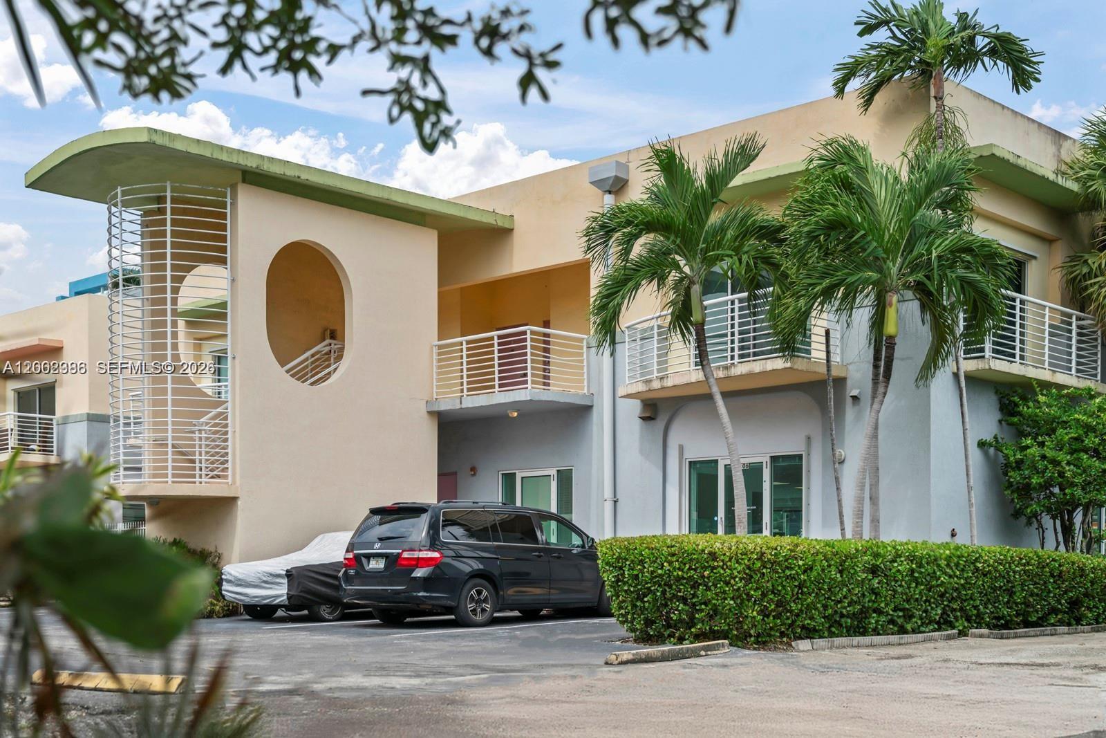 A two-story building with a parking lot, palm trees, and a hedge in the foreground — 200 E Dania Beach Blvd, Dania Beach FL 33004, DANIA BEACH, FL
