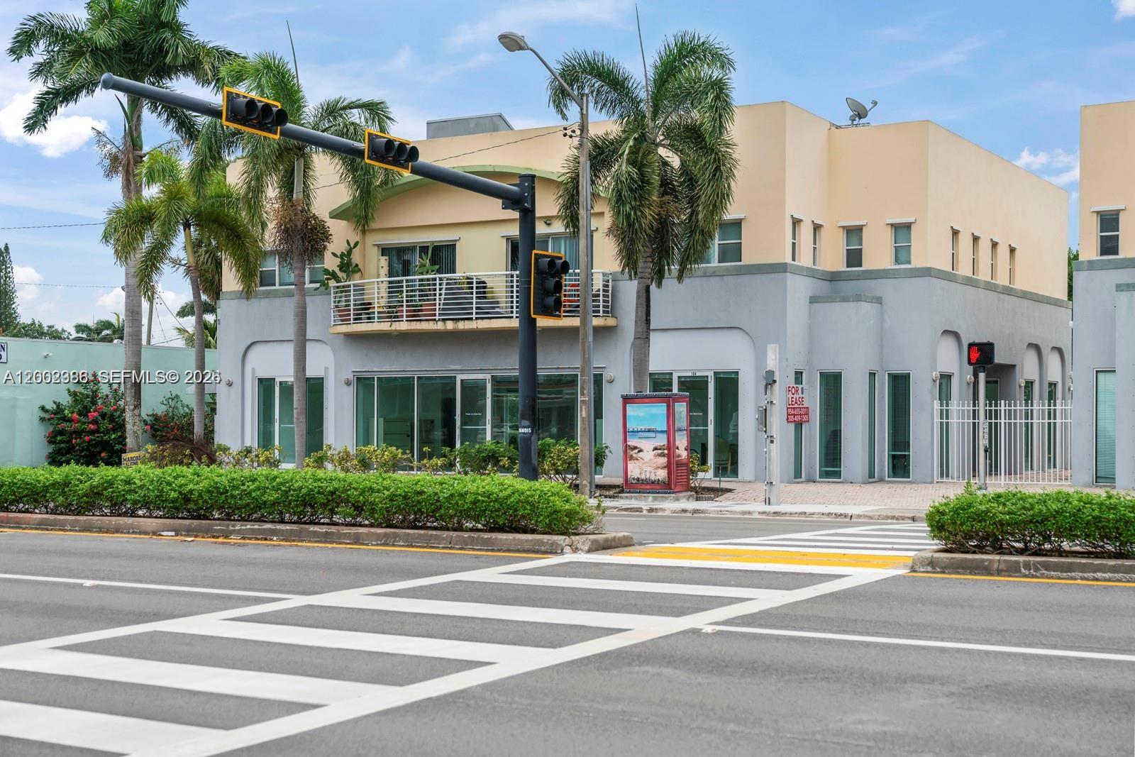 A two-story commercial building with a balcony and ground-floor glass storefronts sits behind a crosswalk — 200 E Dania Beach Blvd, Dania Beach FL 33004, DANIA BEACH, FL