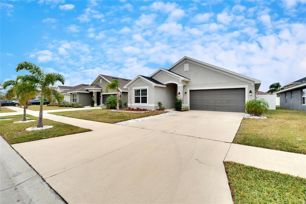 A single-story suburban house with a gray exterior, a two-car garage, and a concrete driveway — 14525 SCOTTBURGH GLEN DRIVE, WIMAUMA, FL