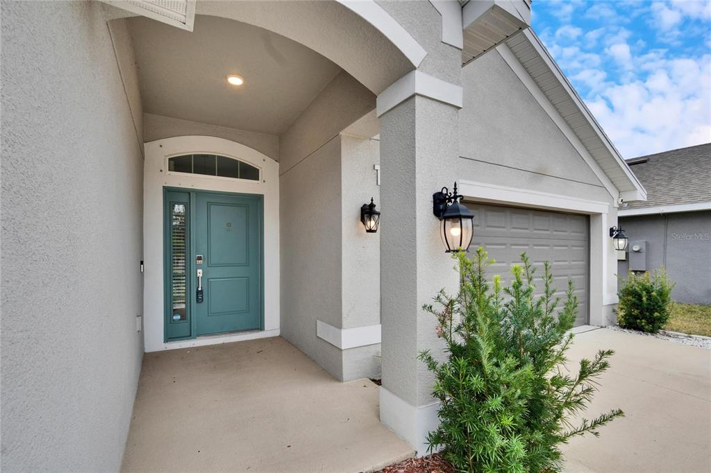 A teal front door with a side window sits under a covered entryway — 14525 SCOTTBURGH GLEN DRIVE, WIMAUMA, FL
