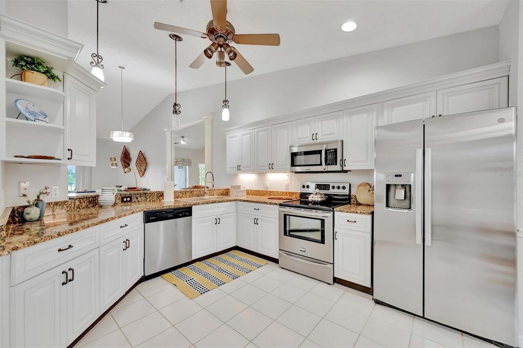 A kitchen with white cabinets, granite countertops, stainless steel appliances, and a ceiling fan — 5240 HYLAND HILLS AVENUE UNIT 1421, SARASOTA, FL