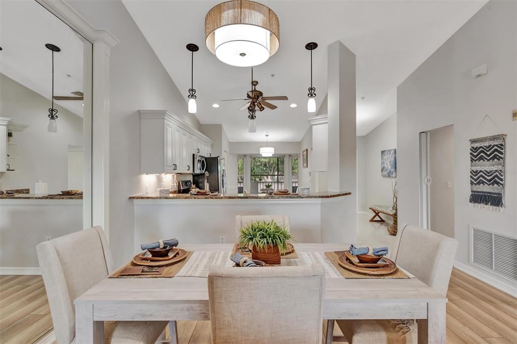 A dining area with a light wood table faces an open kitchen with white cabinets — 5240 HYLAND HILLS AVENUE UNIT 1421, SARASOTA, FL