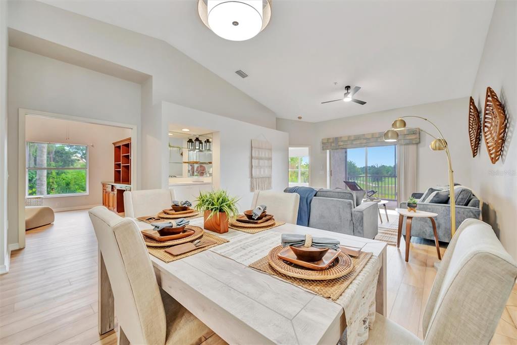 A dining area with a light wood table opens into a living room with balcony views — 5240 HYLAND HILLS AVENUE UNIT 1421, SARASOTA, FL
