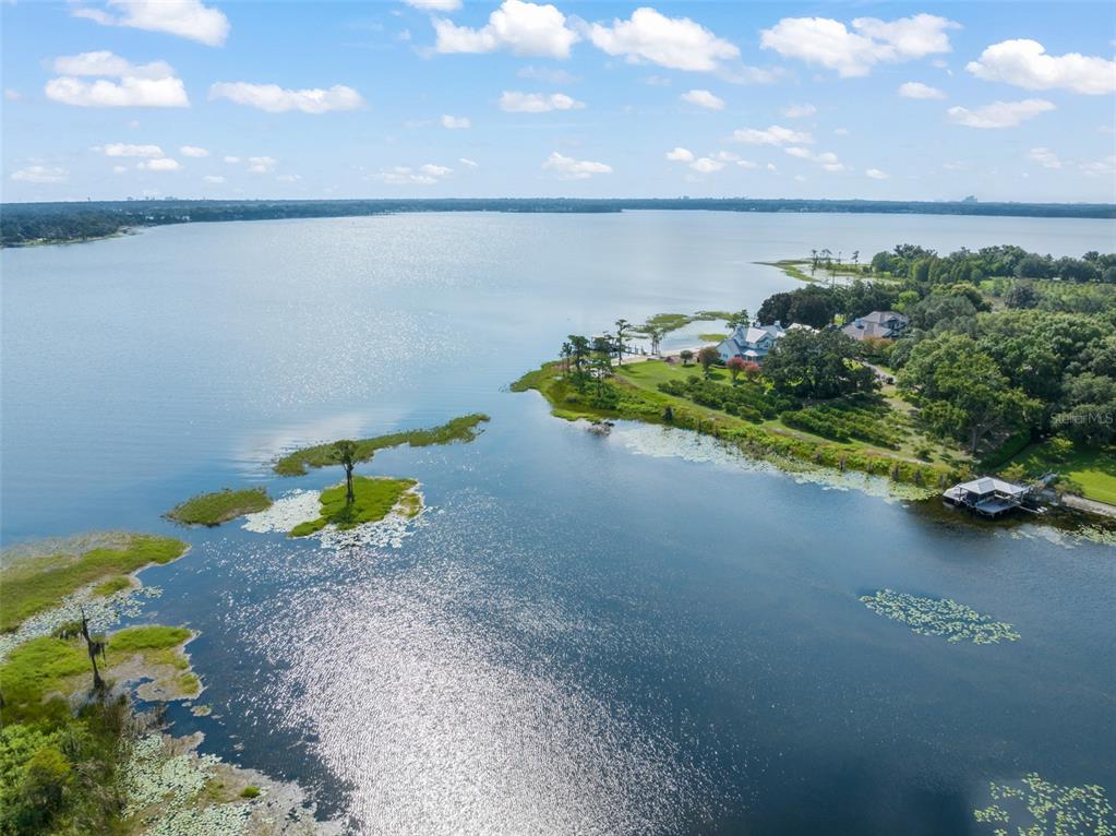 An aerial view shows a house on a point of land extending into a lake — 12624 PARK AVENUE, WINDERMERE, FL