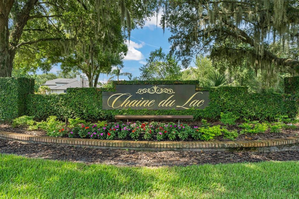A stone sign with the text Chaine du Lac sits in front of a landscaped hedge — 12624 PARK AVENUE, WINDERMERE, FL