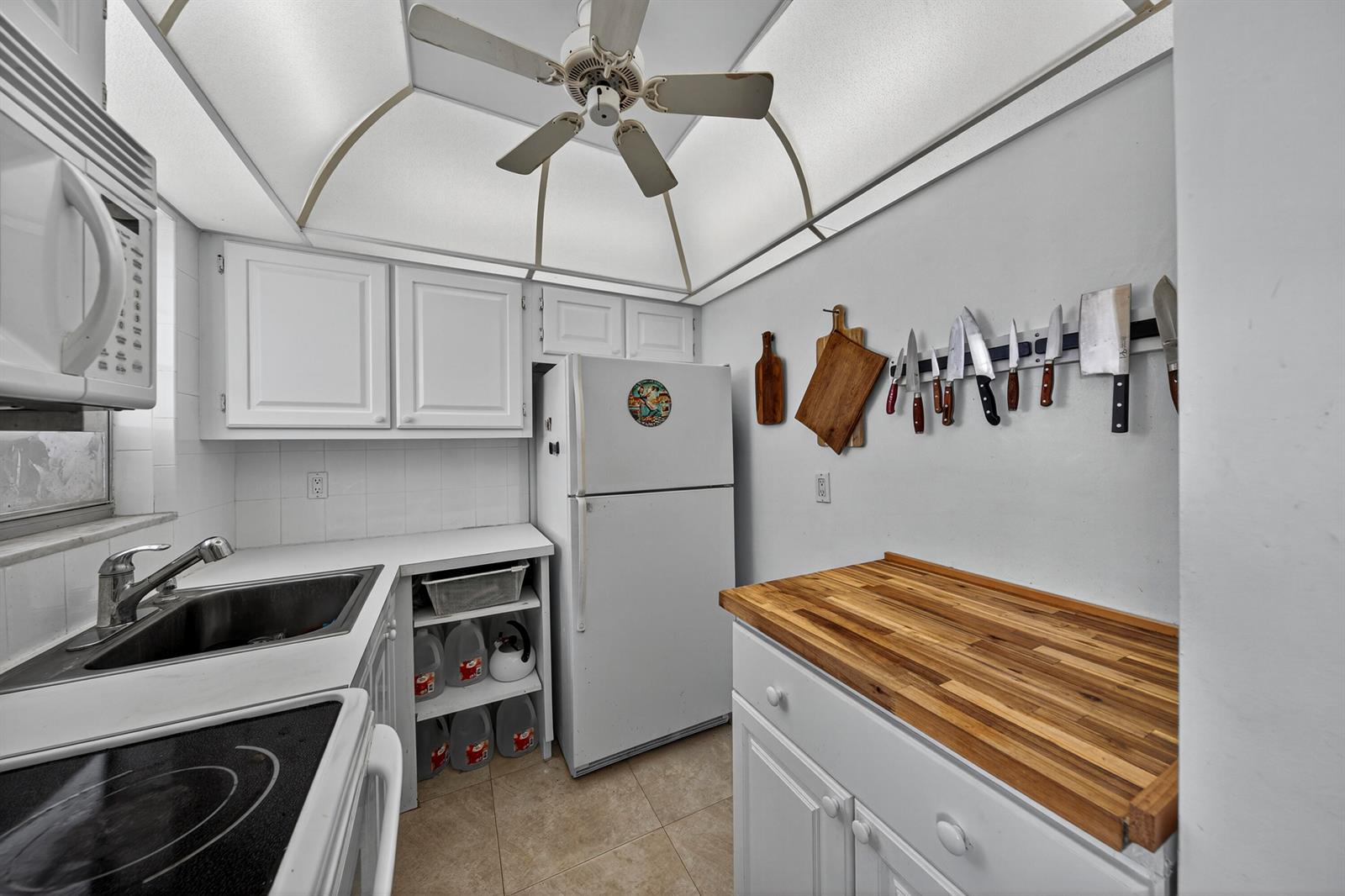 A galley kitchen features white cabinets, a wood countertop, a ceiling fan, and stainless appliances — 251 S GOLF Boulevard # 287, Pompano Beach FL 33064, POMPANO BEACH, FL