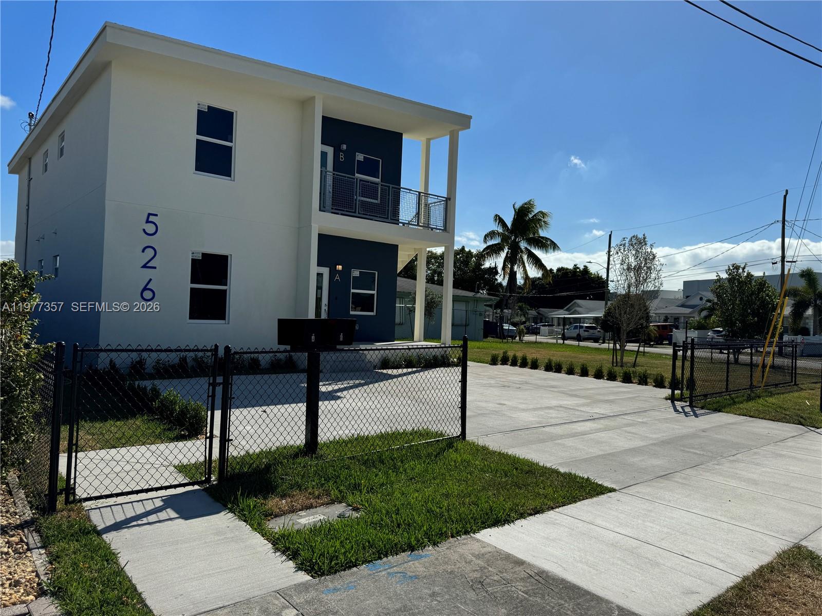 A two-story building with a white and blue exterior features a fenced concrete driveway — 526 NW 6th # A, Hallandale Beach FL 33009, HALLANDALE BEACH, FL