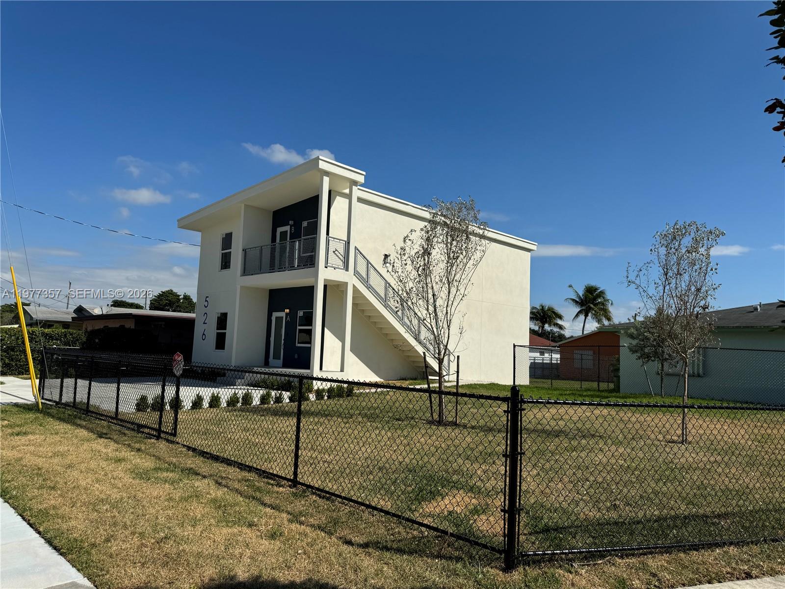 A two-story white building with an exterior staircase and a chain-link fence in front — 526 NW 6th # A, Hallandale Beach FL 33009, HALLANDALE BEACH, FL
