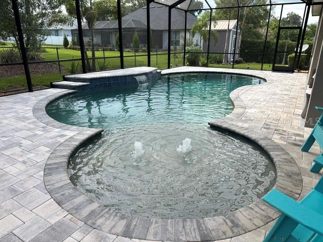 A backyard swimming pool with a spa, water features, and a screened-in patio enclosure — 5111 DISMUKE DRIVE, LAKELAND, FL
