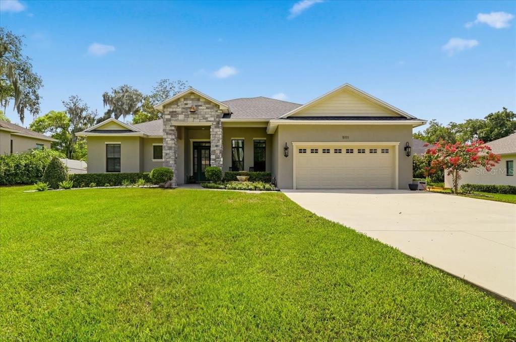 A single-story suburban house with a stone-accented entryway, a two-car garage, and a lawn — 5111 DISMUKE DRIVE, LAKELAND, FL