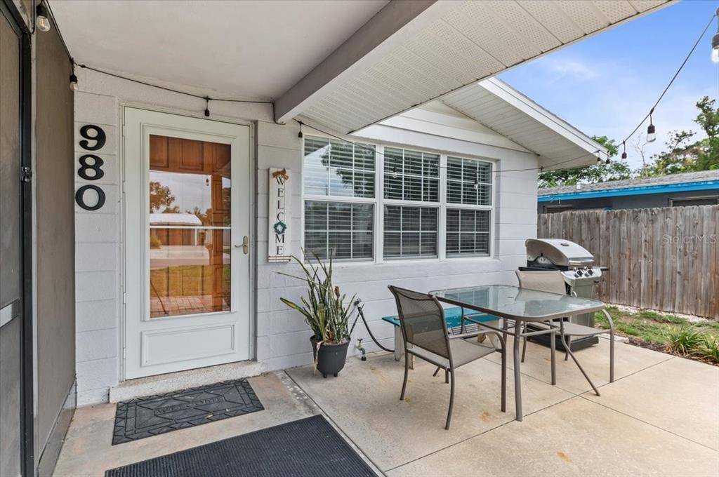 A patio features a glass-top table, chairs, a grill, and a white front door — 980 CHARLOTTE AVENUE, SARASOTA, FL