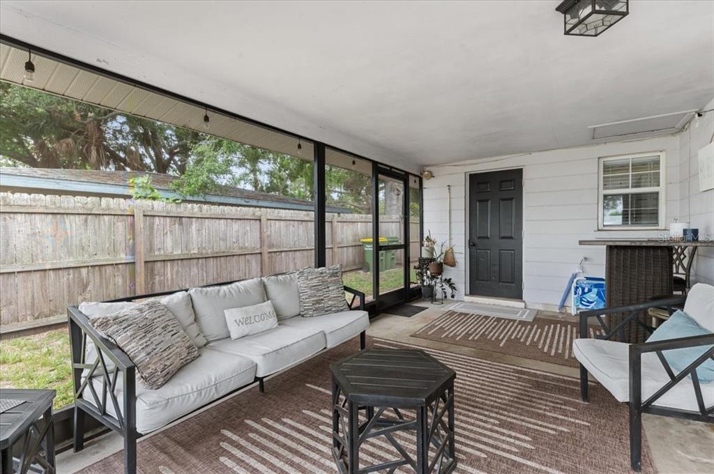A screened-in patio features a sofa, an armchair, a coffee table, and a wooden fence — 980 CHARLOTTE AVENUE, SARASOTA, FL