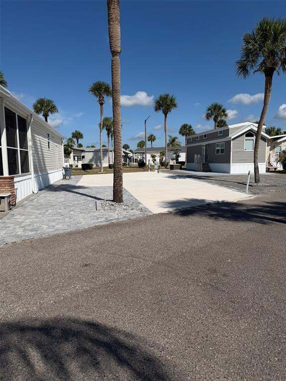 A paved driveway and patio area sit between two manufactured homes under a clear sky — 9000 US HWY 192 UNIT 833, CLERMONT, FL
