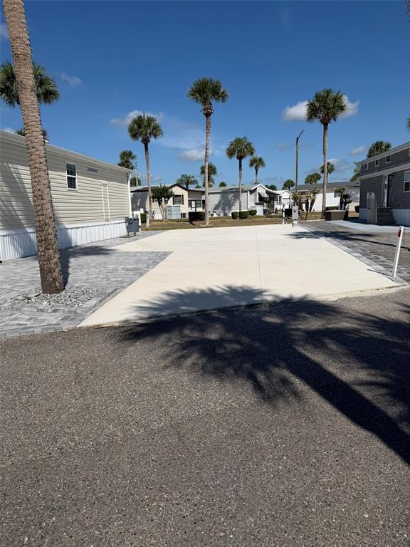 A paved driveway and patio area sit beside a mobile home under palm trees — 9000 US HWY 192 UNIT 833, CLERMONT, FL