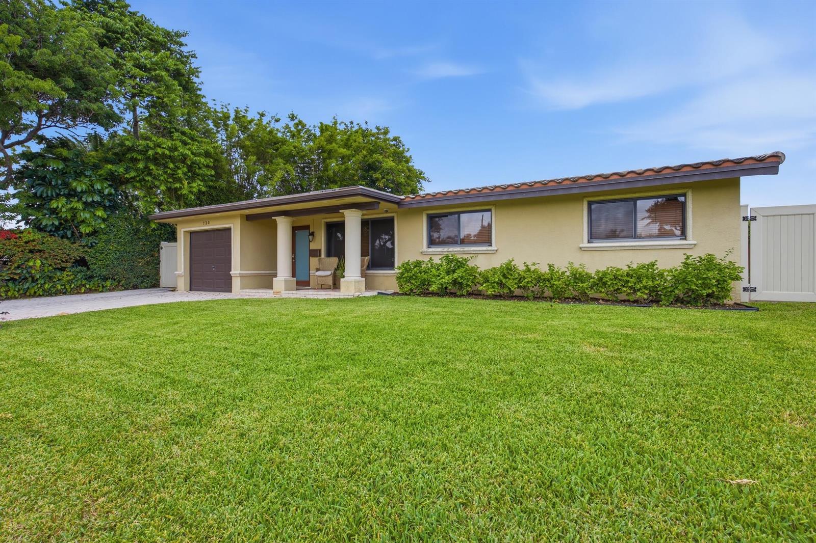 A single-story house with a tan stucco exterior, a brown garage door, and a lawn — 730 SE 3rd Terrace, Pompano Beach FL 33060, POMPANO BEACH, FL