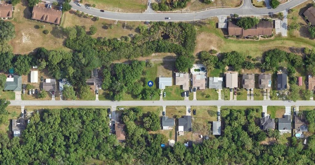 This aerial view shows a residential street with houses, driveways, and surrounding wooded areas — 8165 GULF WAY, HUDSON, FL