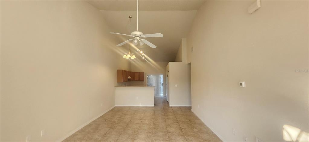 A living room with tile flooring and a ceiling fan leads to a kitchen area — 7411 CANTERBURY STREET, SPRING HILL, FL
