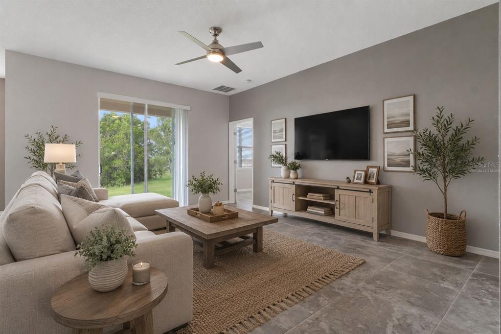A living room features a sectional sofa, a wooden coffee table, and a wall-mounted television — 30798 WATER LILY DRIVE, BROOKSVILLE, FL