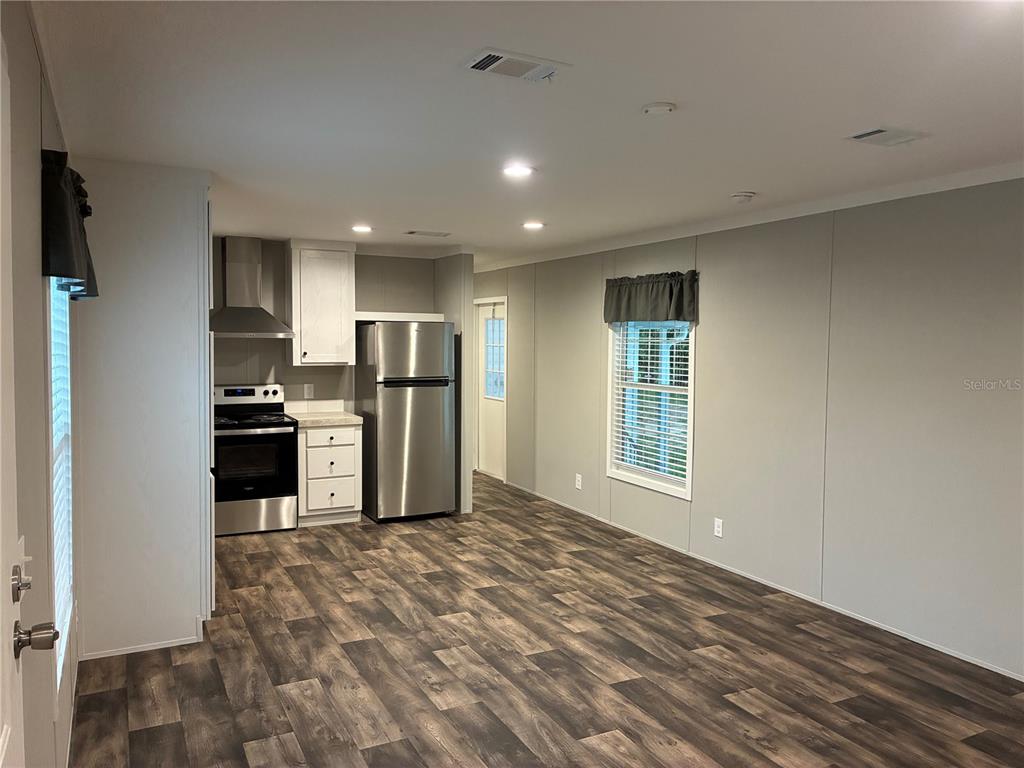 A kitchen and living area feature light gray walls, wood-look flooring, and stainless steel appliances — 263 EDGEWOOD BOULEVARD, LAKE WALES, FL