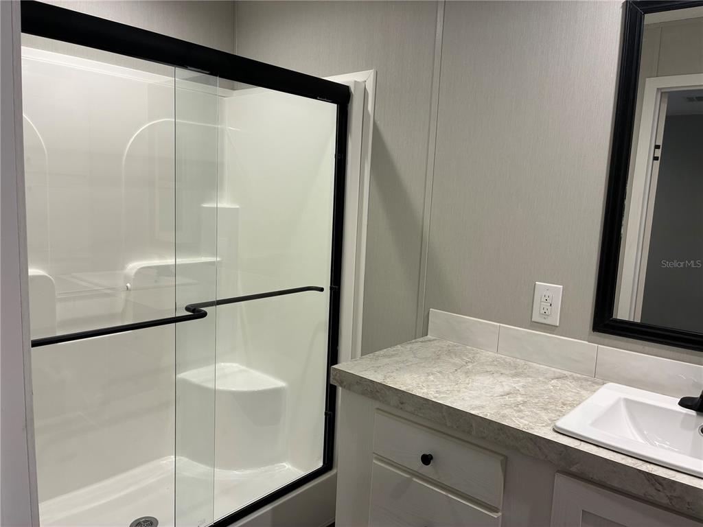 A bathroom features a walk-in shower with sliding glass doors and a white vanity — 263 EDGEWOOD BOULEVARD, LAKE WALES, FL